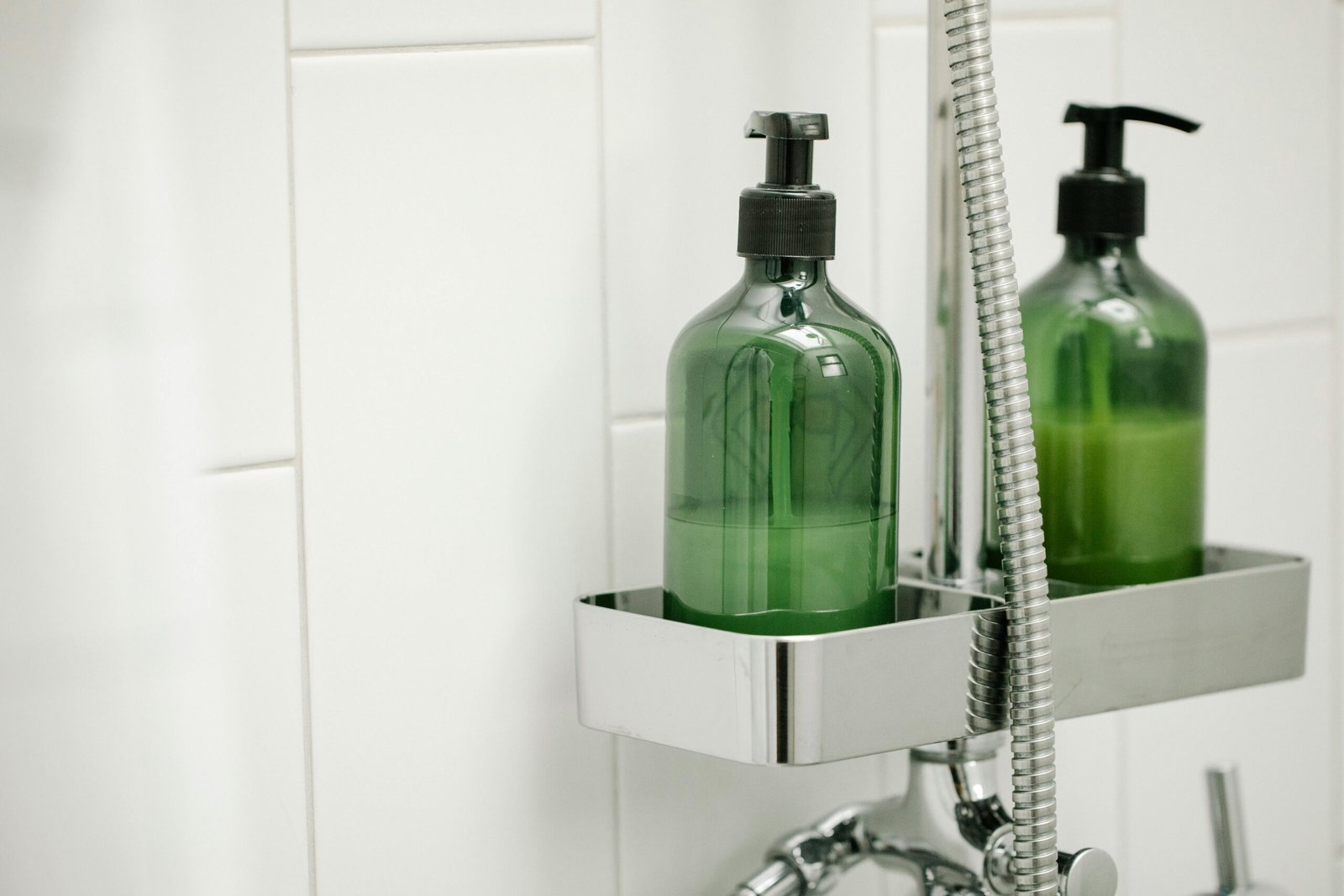 Two green bottles of Shampoo standing side by side, showcasing their sleek design and botanical-inspired packaging.